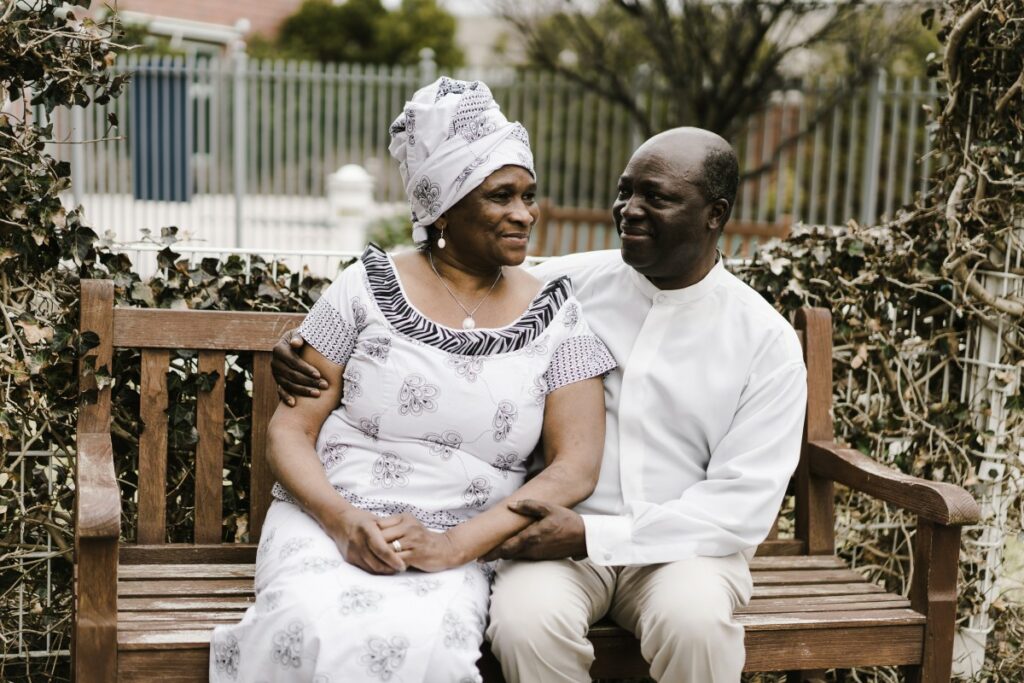 storyblocks-elderly-ghanaian-man-holds-his-wife-lovingly-as-they-sit-on-a-bench_H3Tcya3YP